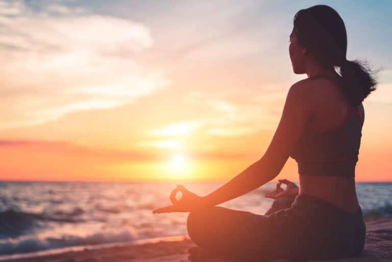 Woman sitting on beach at sunset