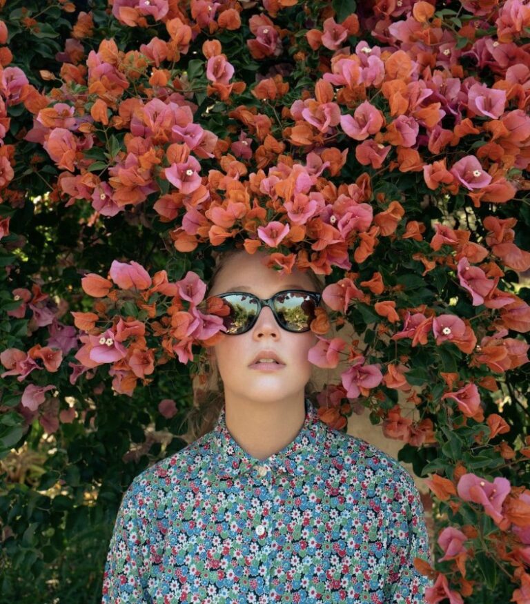 Woman in sunglasses in front of pink flowers